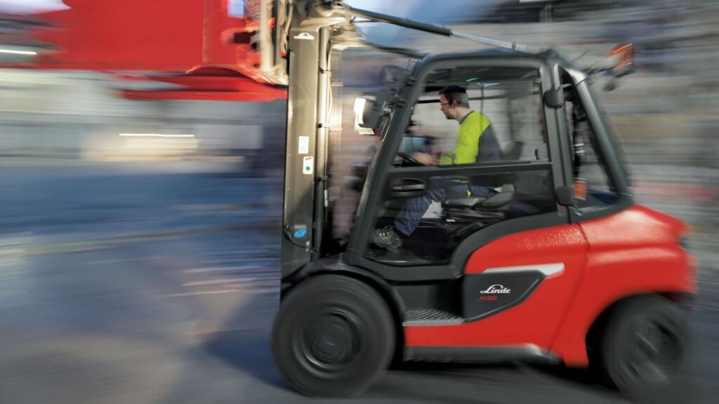 Fotografija pri brzom radu Linde H50 viljuškara u transportu reciklažnog materijala u farbici papira Smurfit Kappa (okruženje viljuškara je zamagljeno, simbolišući veliku brzinu koju Linde viljuškari mogu da postignu)