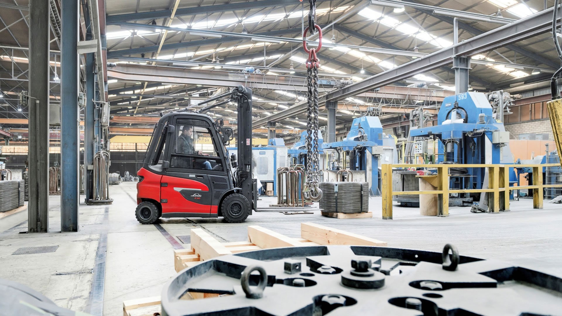 Električni viljuškar Linde E20 radi u zatvorenom industrijskom okruženju među mašinama i opremom