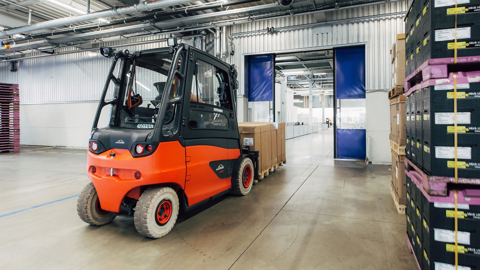 Linde viljuškar vozi teret kroz automatska skladišna vrata uz Linde Door Control sistem za pametno upravljanje i smanjenje oštećenja.