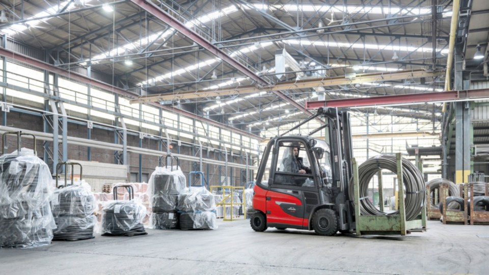 Linde viljuškar u zatvorenom skladištu prenosi metalne kalemove, okružen industrijskom opremom i ambalažom